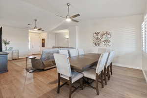 Dining room featuring lofted ceiling, light wood-style floors, baseboards, and a ceiling fan