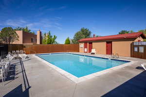 Community pool with a patio area and fence