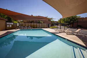 Community pool with a patio area and fence