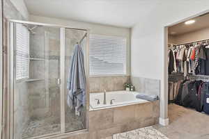 Full bathroom featuring a garden tub, tile patterned floors, a walk in closet, and a shower stall