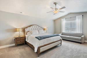 Bedroom with vaulted ceiling, ceiling fan, carpet, and visible vents