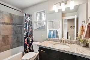 Bathroom with toilet, shower / tub combo, visible vents, and vanity