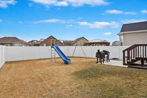 View of yard featuring a fenced backyard, a residential view, a playground, and a patio