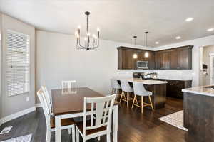 Dining space with baseboards, visible vents, dark wood finished floors, a chandelier, and recessed lighting