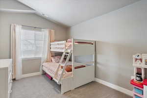 Bedroom with lofted ceiling, light carpet, visible vents, and baseboards