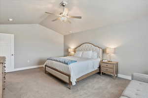 Carpeted bedroom with lofted ceiling, ceiling fan, and baseboards