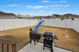 View of yard featuring a fenced backyard, a residential view, a patio area, a mountain view, and a playground