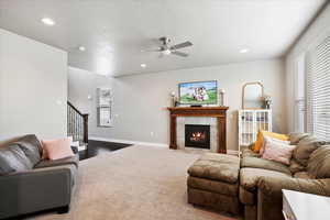 Carpeted living room featuring a textured ceiling, recessed lighting, a fireplace, baseboards, and stairway