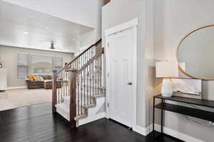 Entryway featuring ceiling fan, a textured ceiling, dark wood-type flooring, baseboards, and stairs