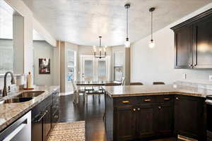 Kitchen with dark wood-style floors, light countertops, a sink, and stainless steel dishwasher