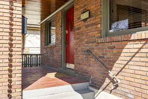 Entrance to property featuring brick siding and a porch