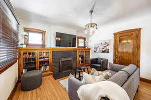 Living area featuring a notable chandelier, wood-type flooring, a fireplace, and baseboards