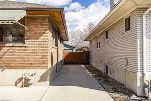 View of side of home featuring fence and brick siding