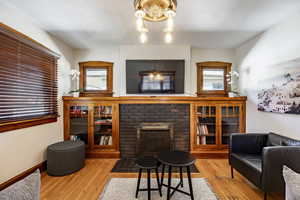 Living area with a chandelier, a fireplace, wood finished floors, and baseboards