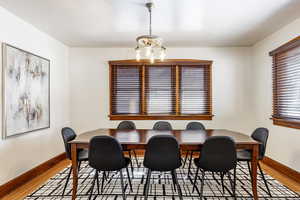 Dining room featuring baseboards, wood finished floors, and a notable chandelier