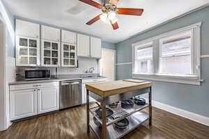 Kitchen with tasteful backsplash, white cabinets, glass insert cabinets, stainless steel appliances, and a sink