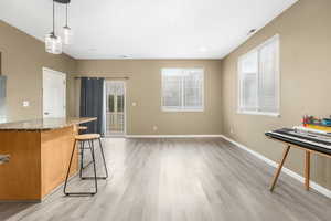 Kitchen featuring light wood finished floors, plenty of natural light, a breakfast bar area, and baseboards