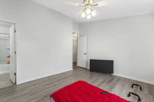 Bedroom featuring baseboards, vaulted ceiling, and wood finished floors