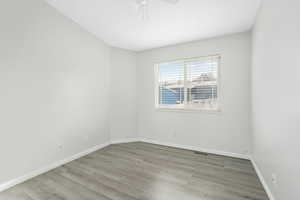 Spare room with visible vents, ceiling fan, baseboards, and wood finished floors