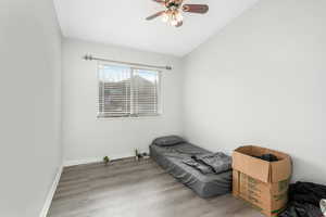 Bedroom with vaulted ceiling, ceiling fan, baseboards, and wood finished floors