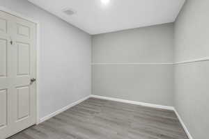 Unfurnished room featuring wood finished floors, visible vents, and baseboards