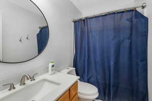 Bathroom with a shower with shower curtain, vanity, and toilet