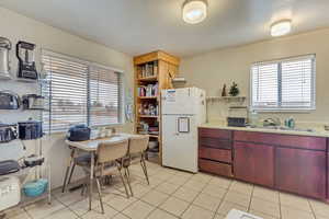 Kitchen featuring open shelves, a sink, freestanding refrigerator, and a healthy amount of sunlight