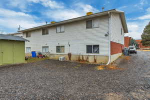 Back of property featuring an outbuilding, driveway, a chimney, and a storage unit