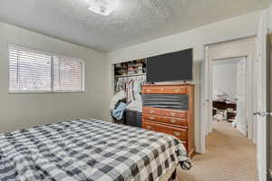 Bedroom featuring a textured ceiling, a closet, and light colored carpet