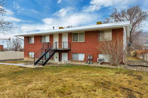 Rear view of property with a yard, brick siding, and fence