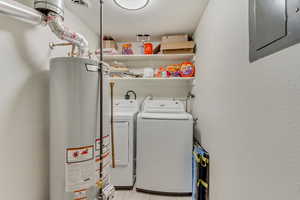 Clothes washing area featuring gas water heater, washing machine and clothes dryer, visible vents, laundry area, and electric panel