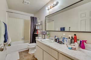 Bathroom featuring toilet, visible vents, vanity, tile patterned floors, and shower / bath combo