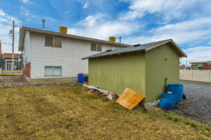 Rear view of property featuring an outbuilding, a lawn, and fence