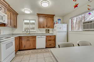 Kitchen featuring a healthy amount of sunlight, white appliances, brown cabinetry, and a sink