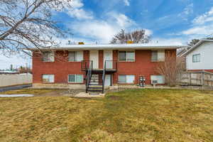 View of front of home featuring a front yard, brick siding, fence, and stairs