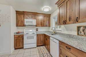 Kitchen with white appliances, a sink, and brown cabinets
