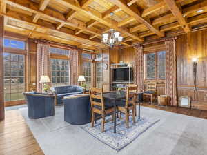 Living area featuring a wood ceiling with exposed beams, wood-type flooring, wood walls, a chandelier, and coffered ceiling