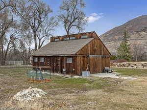 Rear view of property with an outbuilding, a mountain view, roof with shingles, and a yard