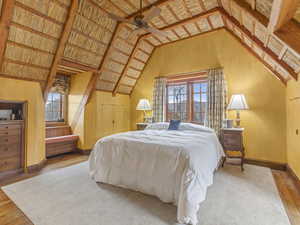 Bedroom featuring hardwood / wood-style flooring, multiple windows, vaulted ceiling, and ceiling fan