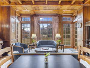 Living room featuring wooden walls, a wood ceiling with exposed beams, and coffered ceiling
