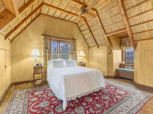 Bedroom with multiple windows, hardwood / wood-style flooring, a ceiling fan, and vaulted ceiling