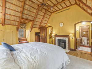 Bedroom with wood-type flooring, a wooden ceiling with exposed beams, high vaulted ceiling, ceiling fan, and a fireplace