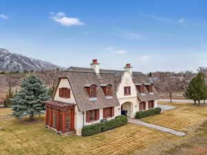View of front of property featuring a chimney, stucco siding, a front yard, a mountain view, and a porch