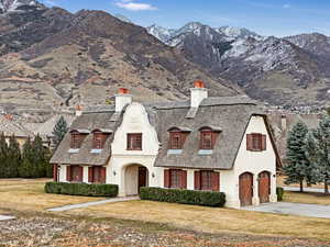 French provincial home featuring a chimney, stucco siding, concrete driveway, and a mountain view