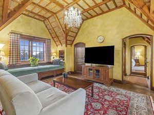 Living area featuring arched walkways, high vaulted ceiling, wood finished floors, a chandelier, and a wood ceiling with exposed beams