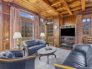 Living area with wooden ceiling with exposed beams, wooden walls, hardwood / wood-style flooring, and coffered ceiling