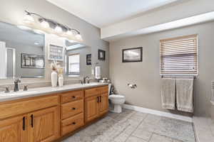 Bathroom featuring double vanity, tile patterned flooring, a sink, and toilet