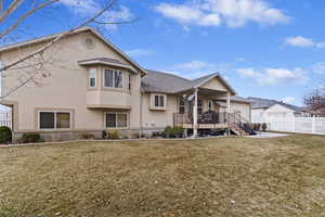 View of front of home with a front yard, roof with shingles, fence, and stucco siding