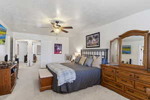 Bedroom with light carpet, ceiling fan, and a textured ceiling