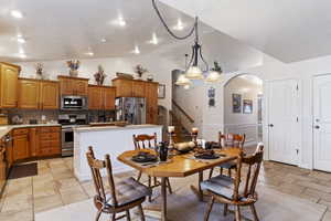 Dining area with arched walkways, a decorative wall, stairway, wainscoting, and vaulted ceiling